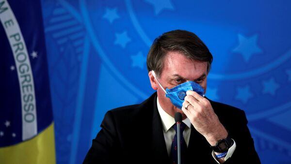 Presidente brasileiro Jair Bolsonaro ajusta sua máscara protetora facial em comunicado à imprensa durante a pandemia de coronavírus, em Brasília, Brasil, 20 de março de 2020 - Sputnik Brasil