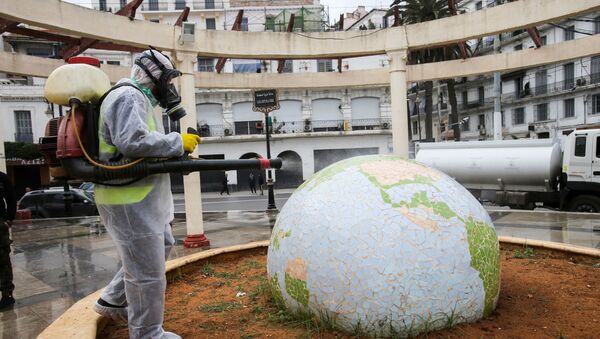 Trabalhador com traje de proteção desinfecta jardim público em forma de globo, em meio à pandemia de coronavírus, em Argel, Argélia, 23 de março de 2020 - Sputnik Brasil