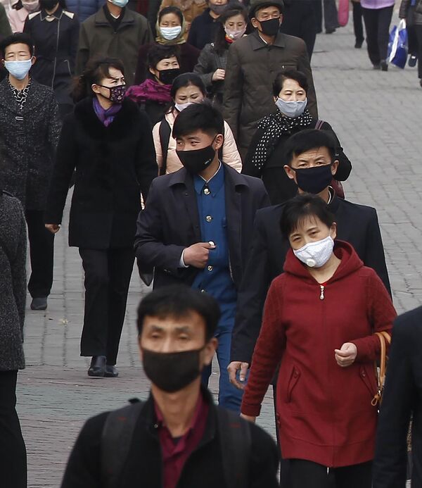 Pessoas caminham com máscaras para se proteger do coronavírus em rua do centro da capital da Coreia do Norte, Pyongyang - Sputnik Brasil