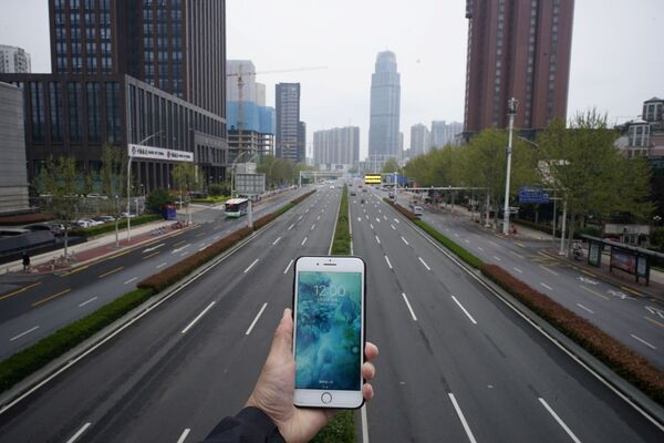 Celular demonstra o horário diante de uma rua vazia em Wuhan, na China - Sputnik Brasil
