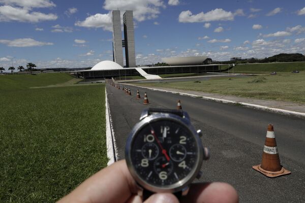 Homem mostra o horário em seu relógio diante do Congresso Nacional em Brasília - Sputnik Brasil