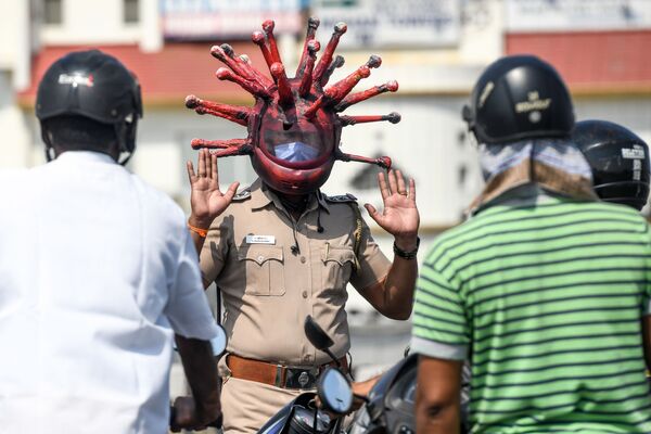 Policial indiano usa um capacete do coronavírus ao passo que conversa com motociclistas sobre a pandemia, enquanto o país vive regime de quarentena - Sputnik Brasil