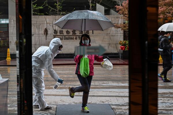 Funcionário de hotel desinfeta hóspede como medida preventiva contra a COVID-19 em Wuhan, China - Sputnik Brasil