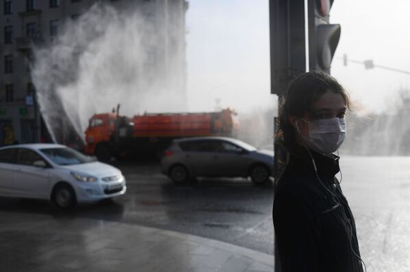 Moça usando máscara espera para atravessar a rua Tverskaya, Moscou, enquanto veículo realiza higienização do local - Sputnik Brasil