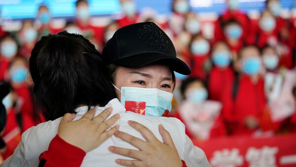 Agentes de saúde chinesas se abraçam no aeroporto de Wuhan, após fim da quarentena na cidade, 8 de abril de 2020 - Sputnik Brasil