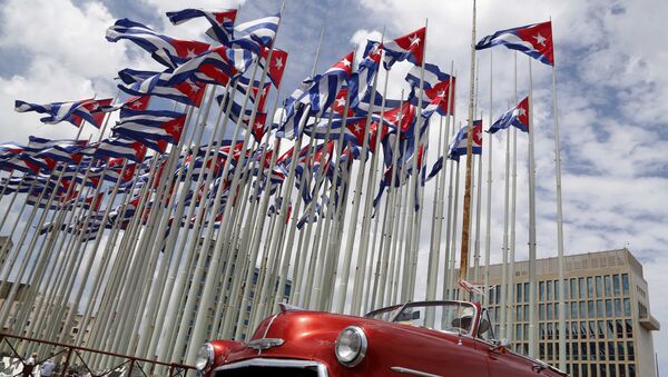 Carro descapotável norte-americano clássico passando ao lado de bandeiras cubanas - Sputnik Brasil