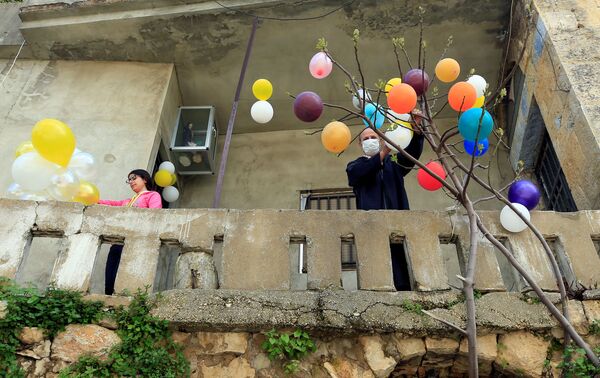 Homem prende balões a uma árvore no Líbano para celebrar a Páscoa na cidade de Jezzine em 12 de abril de 2020 - Sputnik Brasil