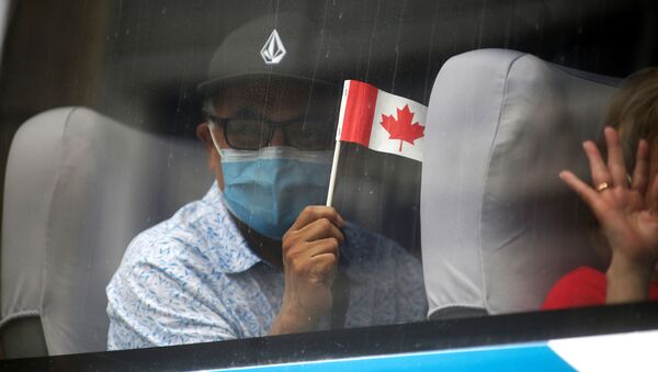 Homem de máscara segurando bandeira do Canadá em um ônibus para voos de repatriação organizados pela embaixada do Canadá no Peru em meio à pandemia do novo coronavírus - Sputnik Brasil
