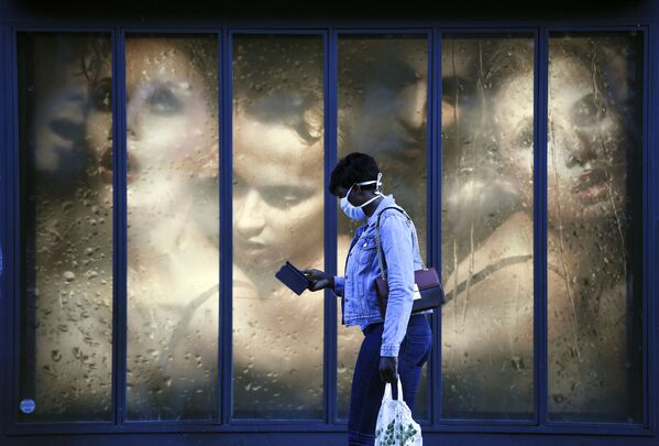 Mulher com máscara protetora passa por vitrine de loja em Paris durante pandemia, França, 14 de abril de 2020 - Sputnik Brasil