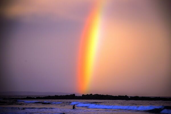 Arco-íris atrás de surfista ao pôr-do-sol na praia de Narrawallee, ao sul de Sydney, Austrália, 10 de abril de 2020 - Sputnik Brasil