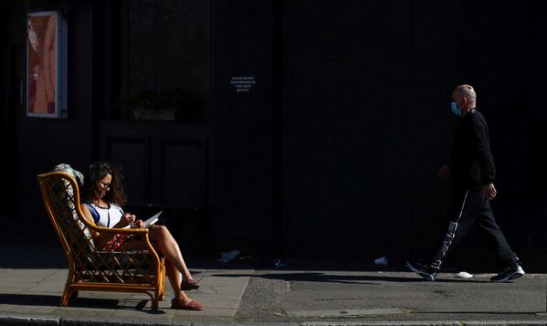 Mulher sentada na cadeira em rua de Dalston, Londres, enquanto a propagação do coronavírus continua, Reino Unido, 14 de abril de 2020 - Sputnik Brasil