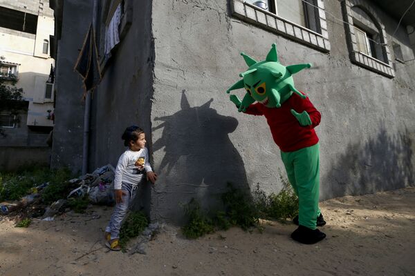 Palestino em fantasia de coronavírus brinca com garotinha na região central da Faixa de Gaza durante a pandemia da COVID-19 - Sputnik Brasil