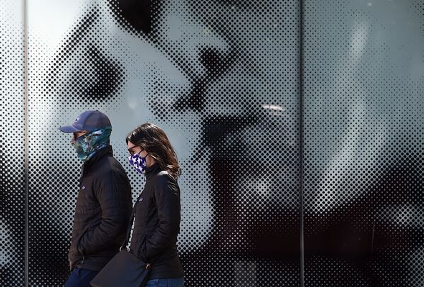 Casal com máscaras passa em frente a cartaz de filme em cinema de Washington, EUA - Sputnik Brasil