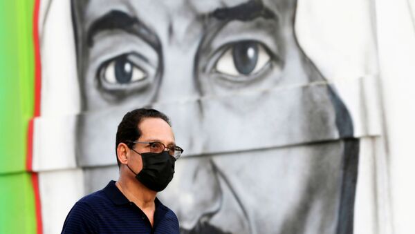 Um homem saudita caminha de máscara em frente a uma imagem do rei Salma bin Abdulaziz, em Riade, no dia 25 de março de 2020. - Sputnik Brasil