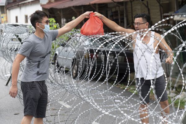 Homem passando sacola através de arame farpado na Malásia
 - Sputnik Brasil