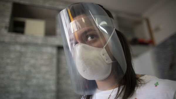 Uma mulher usando máscara e escudo facial (foto de arquivo) - Sputnik Brasil