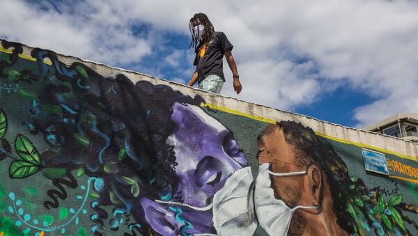 Homem usa máscara protetora próximo a muro grafitado por Marcos Costa, em Salvador - Sputnik Brasil
