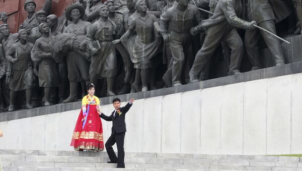 Casal diante de monumento em Pyongyang, na Coreia do Norte - Sputnik Brasil