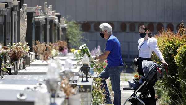 Homem usando máscara facial protetora coloca flores em um túmulo no cemitério de Catânia, que reabriu hoje, quando a Itália inicia um desconfinamento gradual em meio à propagação da doença do coronavírus (COVID-19), Itália, 5 de maio de 2020 - Sputnik Brasil