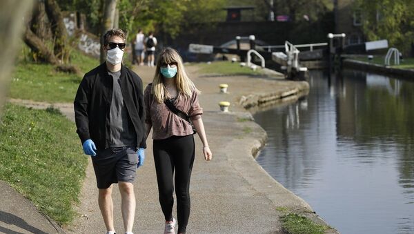 Casal anda com máscaras como prevenção da COVID-19 no Reino Unido (foto de arquivo) - Sputnik Brasil