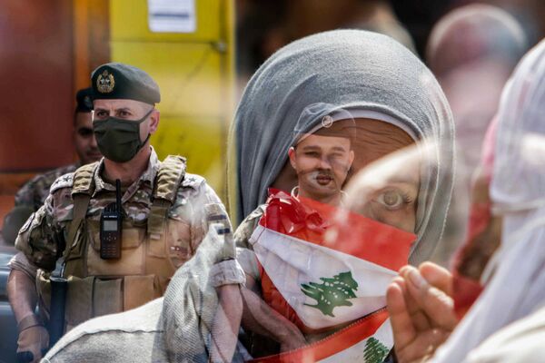 Participante de manifestação no Líbano com máscara com o desenho da bandeira do seu país em frente a soldado na cidade libanesa de Trípoli - Sputnik Brasil