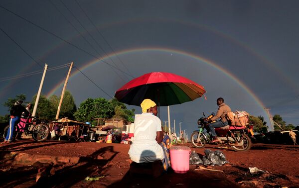 Arco-íris duplo por cima de mulher carregando guarda-chuva e vendendo comida em via do condado de Siaya, no Quênia - Sputnik Brasil