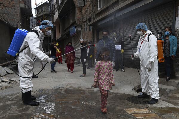 Agentes de saúde borrifam desinfetante em criança durante isolamento total imposto pelo governo em Catmandu, Nepal - Sputnik Brasil