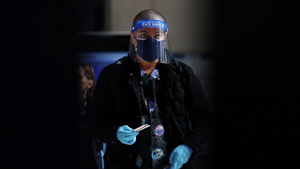 Homem com máscara facial, viseira e luvas é visto na Estação Waterloo, em Londres, Reino Unido - Sputnik Brasil