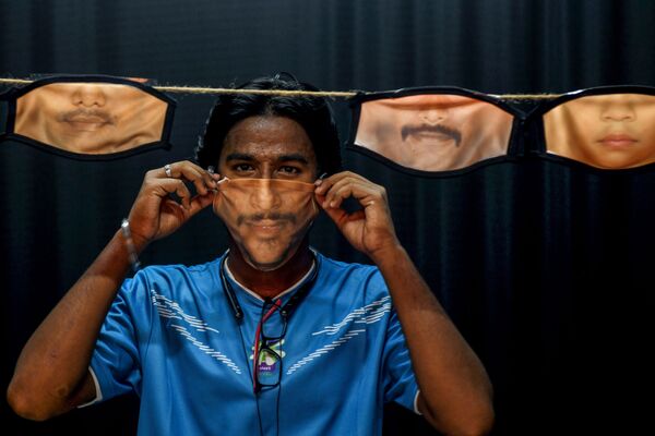 Homem coloca máscara com desenho de rosto durante a pandemia do coronavírus em Chennai, na Índia - Sputnik Brasil