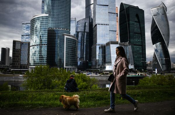 Moça caminha com seu cachorro tendo ao fundo o centro de negócios Moscow City, em Moscou - Sputnik Brasil