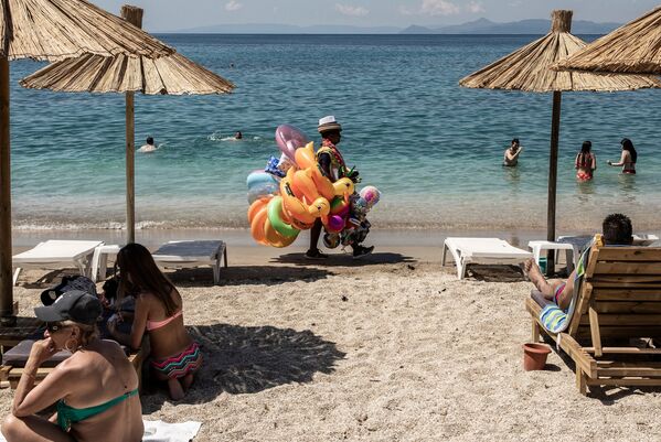 Banhistas descansam e homem vende boias na praia de Alimos nos arredores de Atenas, na Grécia - Sputnik Brasil