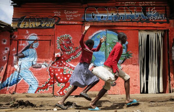 Crianças correm pela rua passando por mural informativo alertando sobre os perigos do novo coronavírus em favela de Nairóbi, no Quênia, 3 de junho de 2020 - Sputnik Brasil