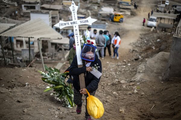 Parente de uma suposta vítima da COVID-19 carrega cruz durante o enterro no cemitério Nueva Esperanza, um dos maiores da América Latina, nos arredores do sul de Lima em 30 de maio de 2020 - Sputnik Brasil