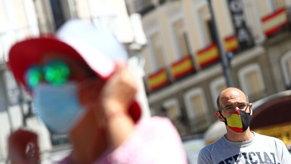 Homem usando máscara facial protetora com bandeira espanhola olha enquanto as pessoas se juntam para fazer um minuto de silêncio durante o último dos dez dias de luto oficial em memória dos que morreram da doença do coronavírus (COVID-19), praça Puerta del Sol, em Madri, Espanha, 5 de junho de 2020 - Sputnik Brasil