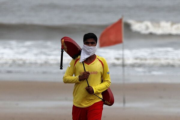 Salva-vidas caminha com máscara improvisada em praia na Índia antes da chegada do ciclone Nisarga - Sputnik Brasil