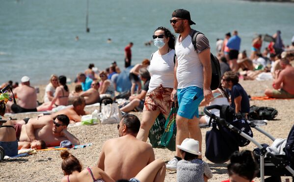Mulher com máscara para se proteger do coronavírus em praia do Reino Unido - Sputnik Brasil