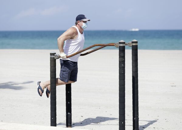 Homem se exercita com máscara de proteção do coronavírus em praia da Flórida, nos EUA - Sputnik Brasil