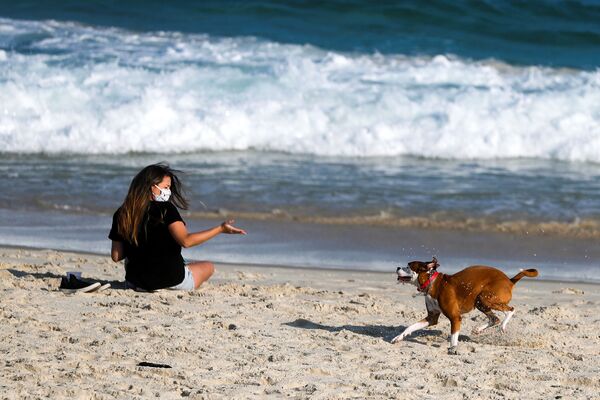 Garota com máscara brinca com seu cachorro em praia do Pepê, no Rio de Janeiro - Sputnik Brasil