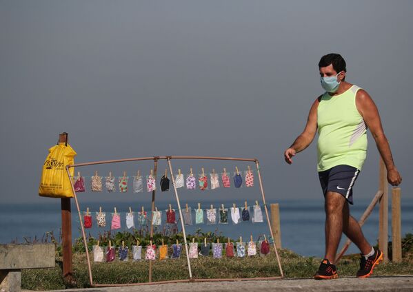 Homem caminha em frente a ponto de venda de máscaras de proteção do coronavírus em praia da Barra da Tijuca, no Rio de Janeiro - Sputnik Brasil