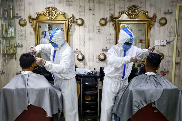 Barbeiros trabalhando com trajes sanitários durante a pandemia do coronavírus em Daca, Bangladesh - Sputnik Brasil