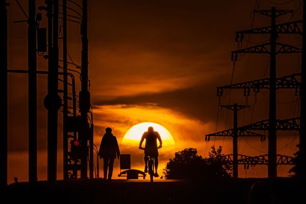 Homem anda de bicicleta tendo como fundo o pôr do sol em Moscou - Sputnik Brasil