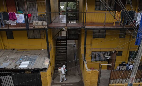 Funcionário da Prefeitura de Santiago, no Chile, executa desinfecção em residências de classe baixa na cidade - Sputnik Brasil