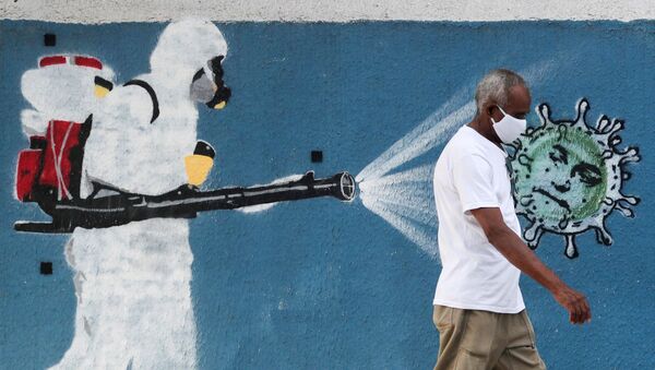 Homem caminha em frente a grafite retratando profissional de limpeza de máscara espalhando coronavírus - Sputnik Brasil
