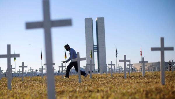 Em Brasília, um ativista caminha em frente a cruzes que simbolizam os mortos pela COVID-19. O protesto contra o presidente brasileiro, Jair Bolsonaro, aconteceu em 28 de junho de 2020, em frente ao Congresso Nacional. - Sputnik Brasil