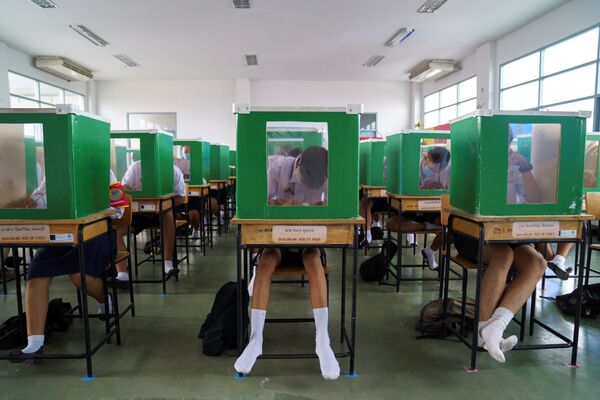 Estudantes da escola Sam Khok usando máscaras faciais se protegendo do vírus dentro de antigas urnas de voto - Sputnik Brasil