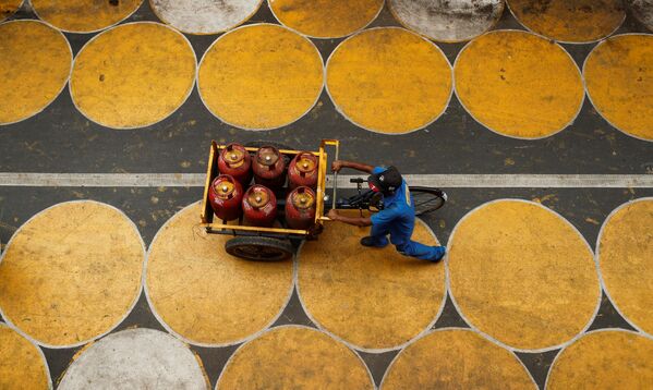 Homem empurra um carrinho com botijas de gás de petróleo liquefeito em Mumbai, Índia
 - Sputnik Brasil