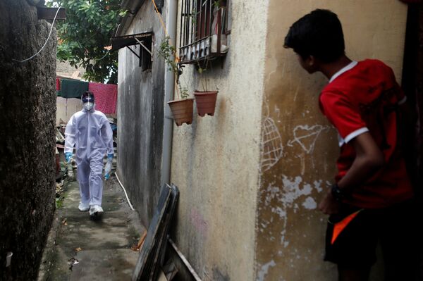 Profissional da saúde com traje de proteção individual passa por favela em Mumbai, Índia - Sputnik Brasil