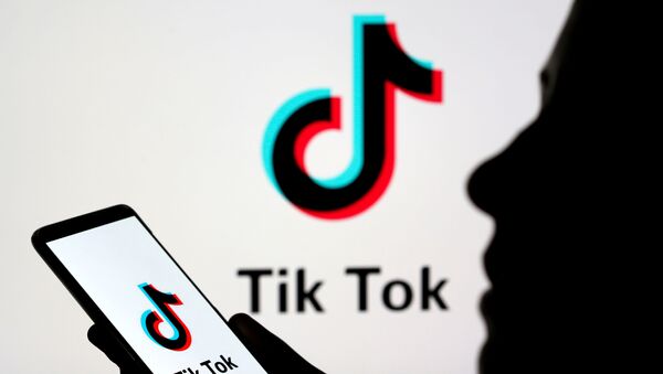 Uma pessoa segura um smartphone com o logotipo do TikTok - Sputnik Brasil