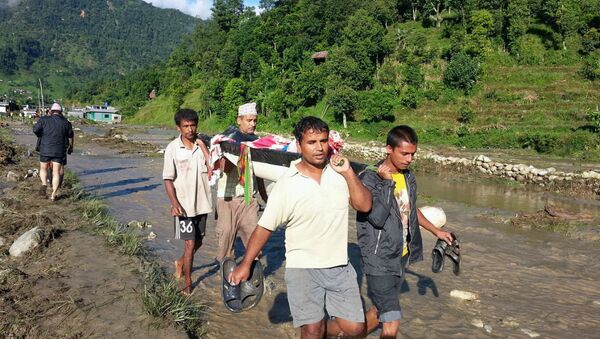 Moradores de um dos vilarejos atingidos por delizamentos no Nepal socorrem uma vítima. - Sputnik Brasil