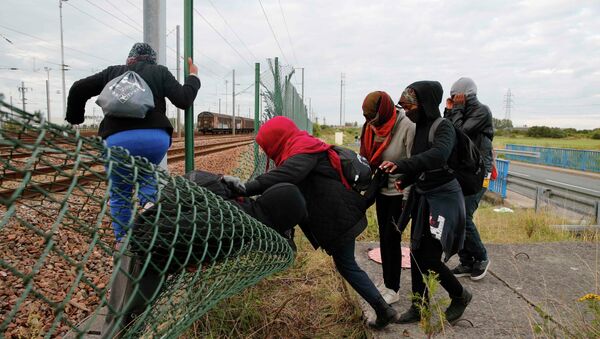 Imigrantes tentando abrir caminho através de cerca junto à linha férrea perto de Calais, na França (29 de julho de 2015). - Sputnik Brasil
